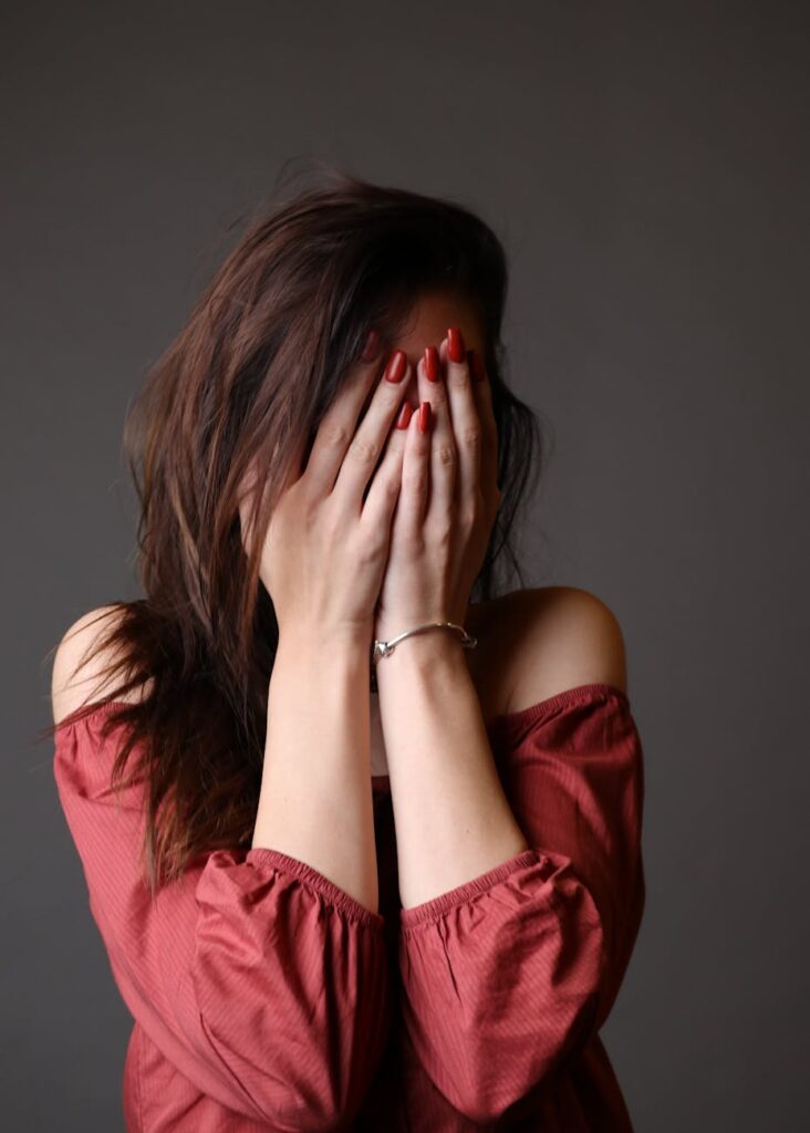 standing woman hiding face with both hands